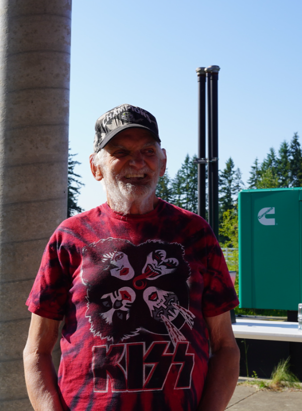 Man outside smiling in baseball cap with red KISS t-shirt