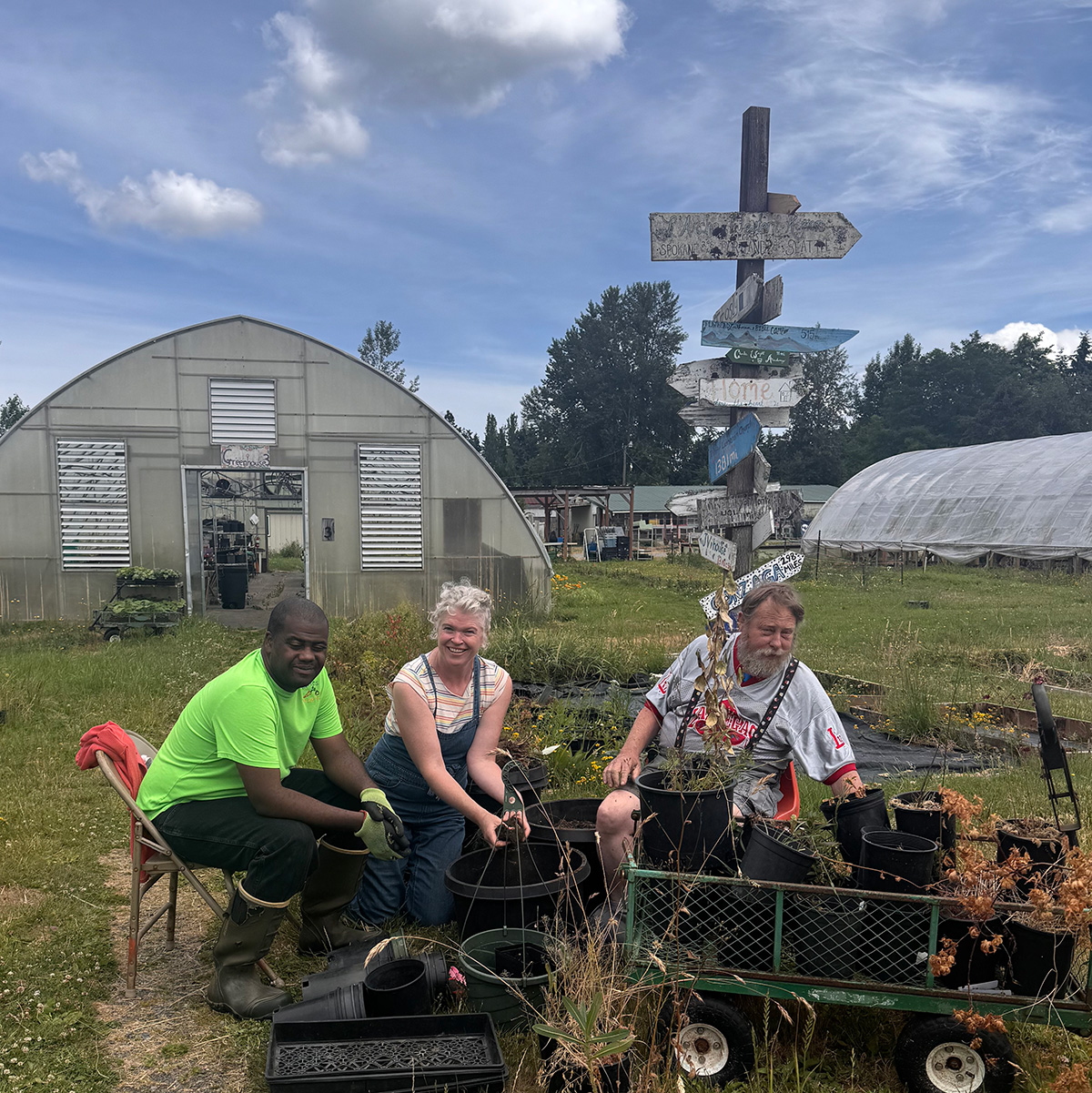 Three people in front of greenhouse. 