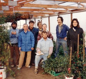 Older photo with people inside next to plants. 